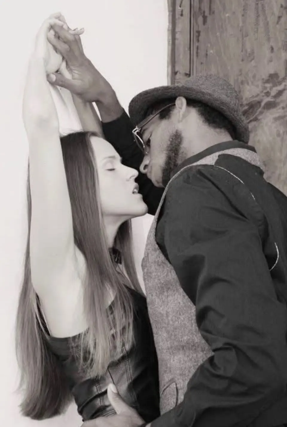 A couple leaning close in an intimate moment against a wall